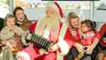 Santa Claus playing the accordion to families